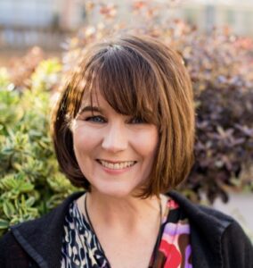 Photo of a woman smiling in front of trees