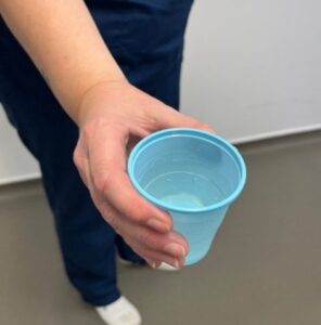 A staff member holding a blue cup 